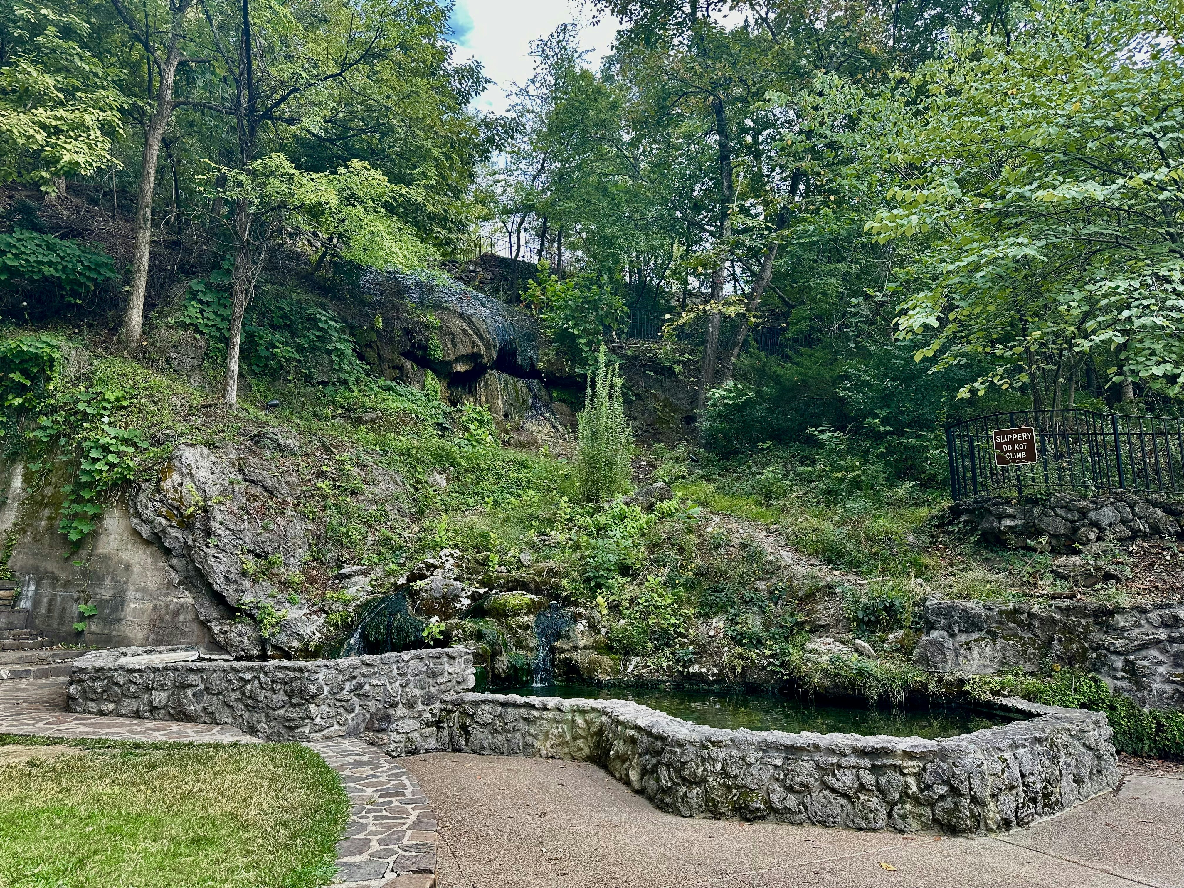 a stone bench sitting on top of a lush green hillside