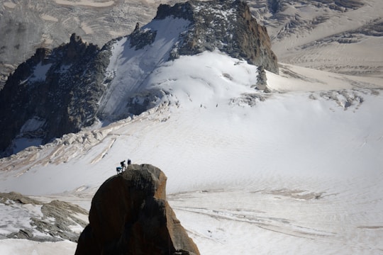 A group of climbers reaching a snowy mountain summit at sunrise.