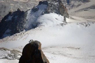 A group of climbers reaching a snowy mountain peak at sunrise, celebrating their achievement.