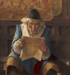 An elderly man wearing spectacles and a black cap intensely reads a document. He is dressed in 18th-century clothing with a blue coat, ruffled white shirt, and brown pants. The setting appears to be historic, with richly adorned woodwork in the background.