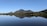 A serene landscape with a peaceful lake reflecting the surrounding trees and mountains.