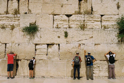 A group of volunteers carefully restoring an ancient stone wall at Bimbia heritage site.