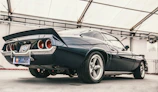 Side view of a classic muscle car with glossy paint under bright lights.