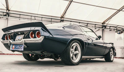 Side view of a classic muscle car with glossy paint under bright lights.