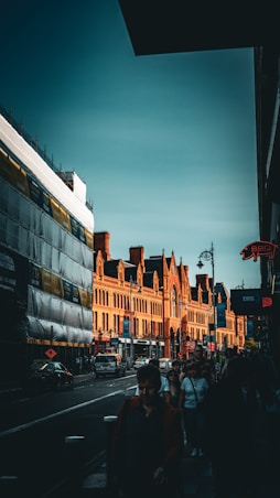 a group of people walking down a street next to tall buildings
