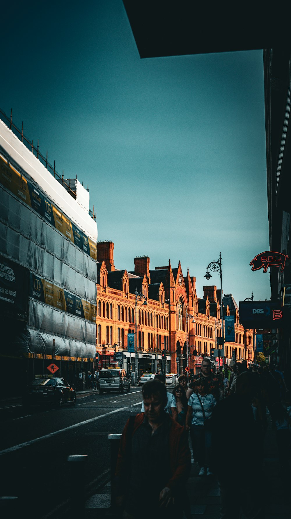 a group of people walking down a street next to tall buildings