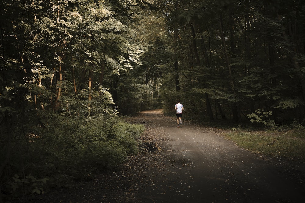 a person walking down a dirt road in the woods
