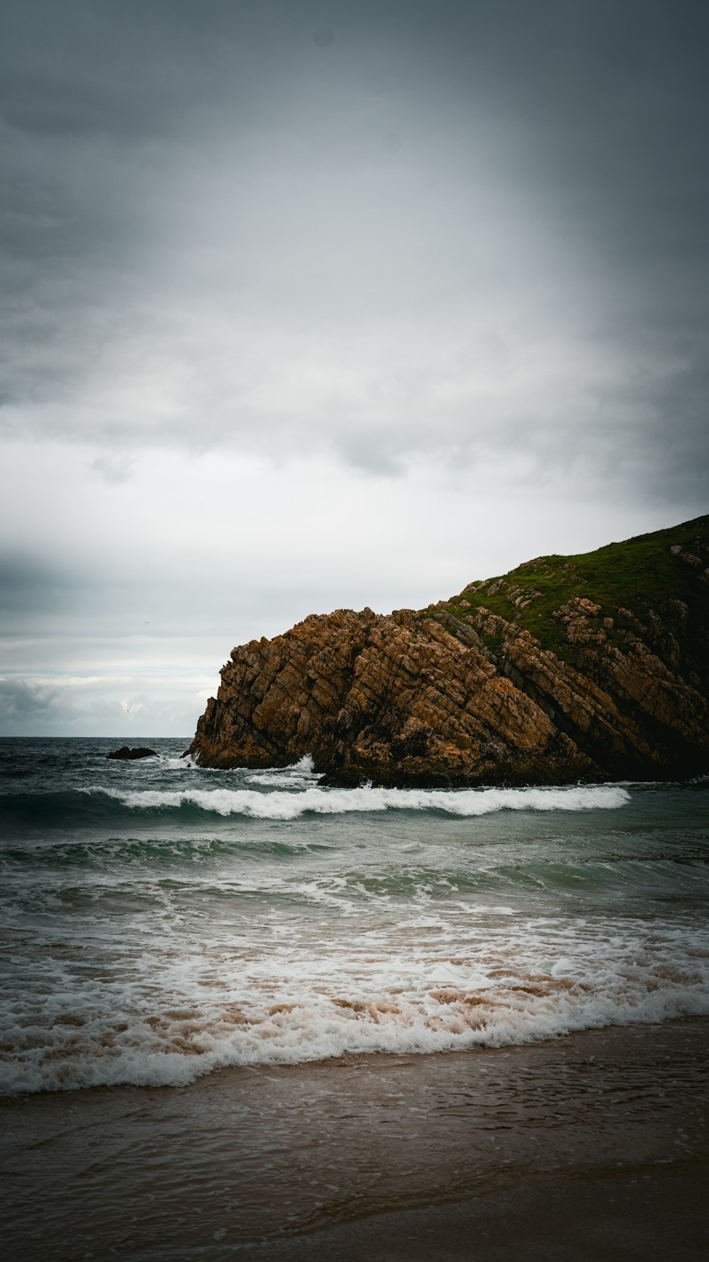 a rock outcropping in the ocean on a cloudy day