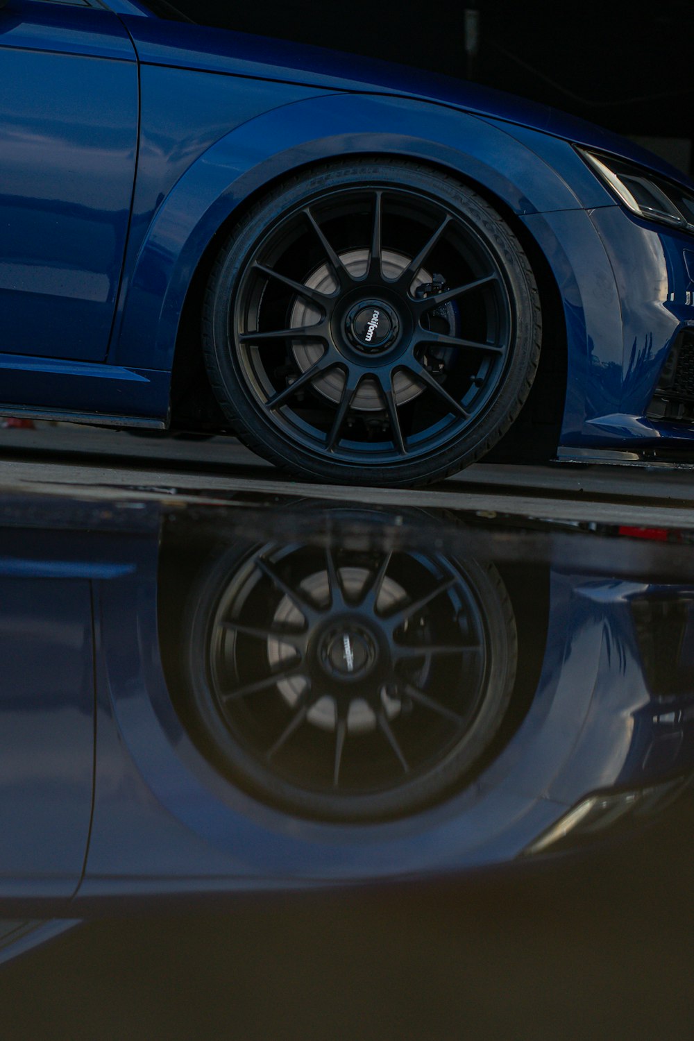 a close up of a blue sports car on a reflective surface