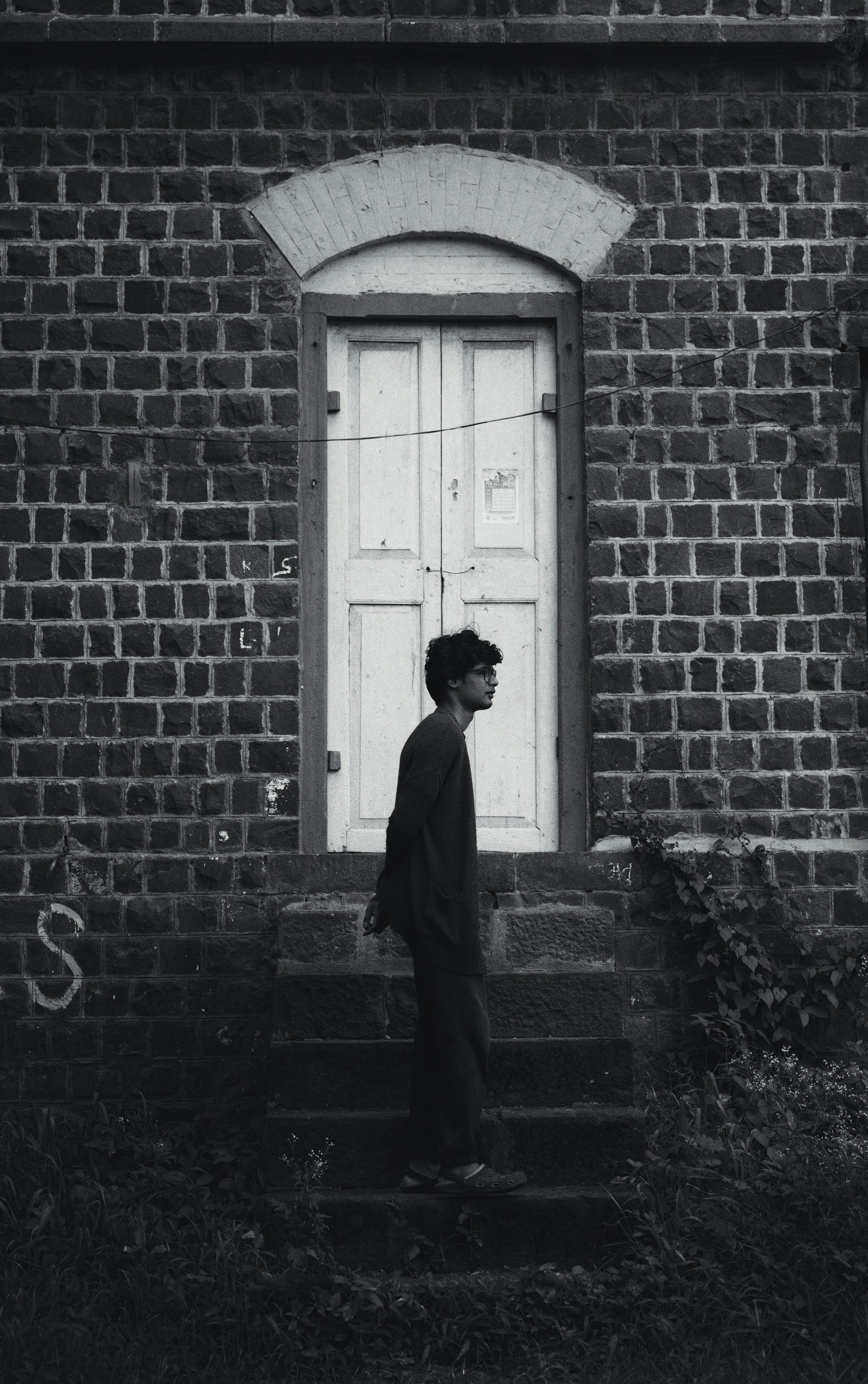a black and white photo of a man standing in front of a door