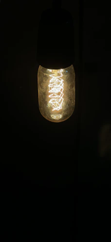 A bright LED bulb glowing warmly against a dark background