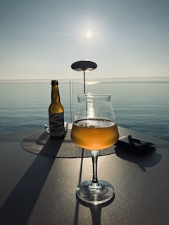 A picturesque sunset view with a bottle of anis carteluo on a table.