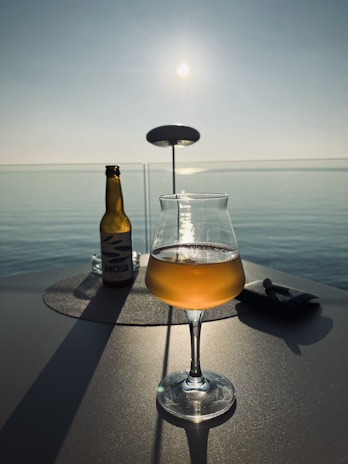 A picturesque sunset view with a bottle of anis carteluo on a table.