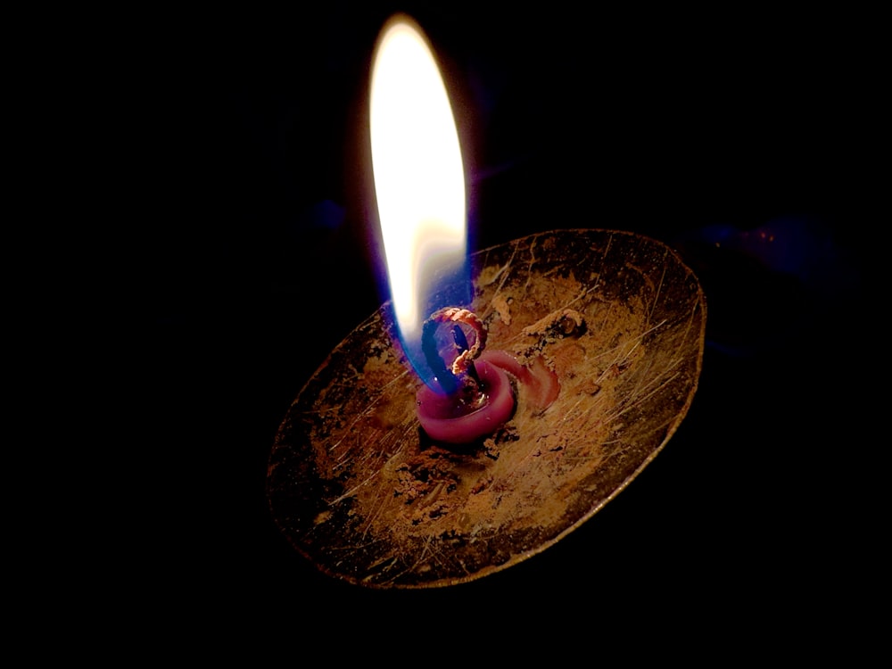 a lit candle sitting on top of a wooden plate