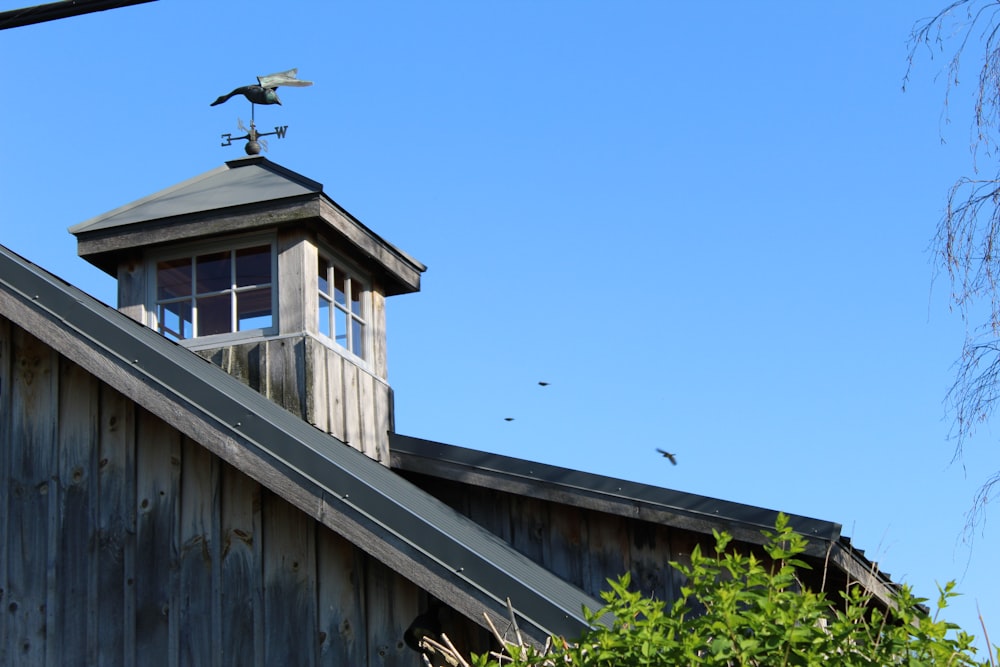 a tall wooden building with a weather vane on top of it