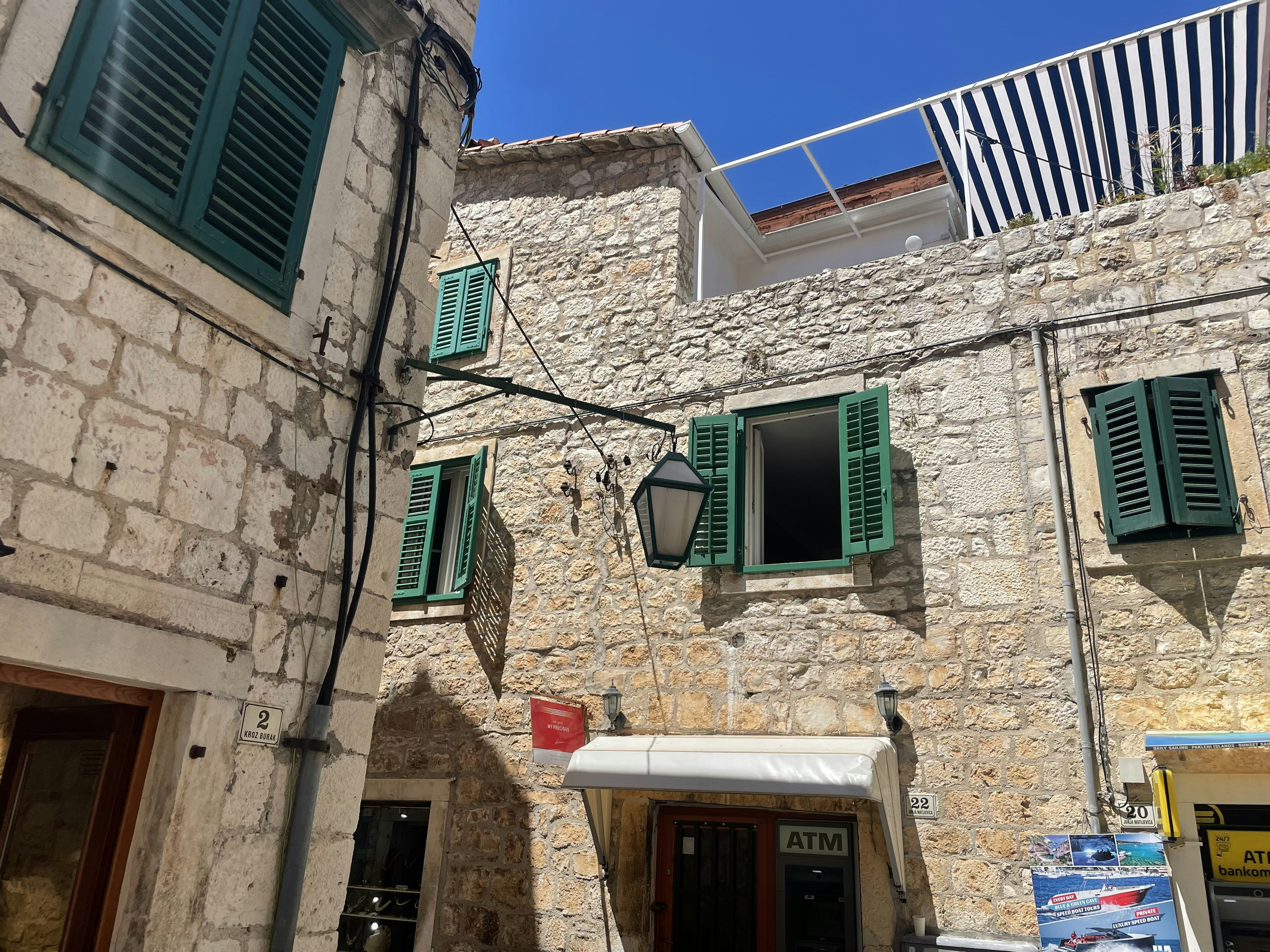 a stone building with green shutters and a white awning
