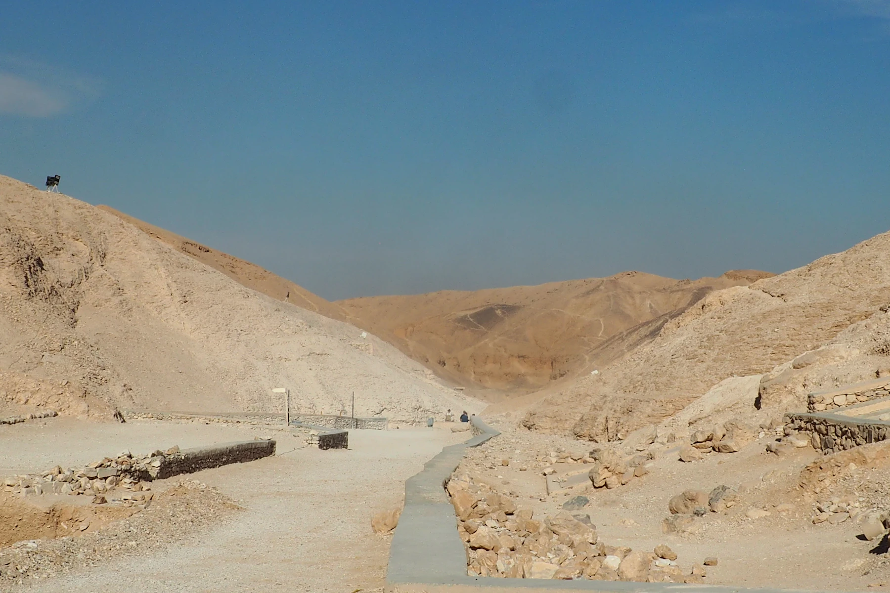 A path crosses dry ground between limestone cliffs in the Valley of the Kings.