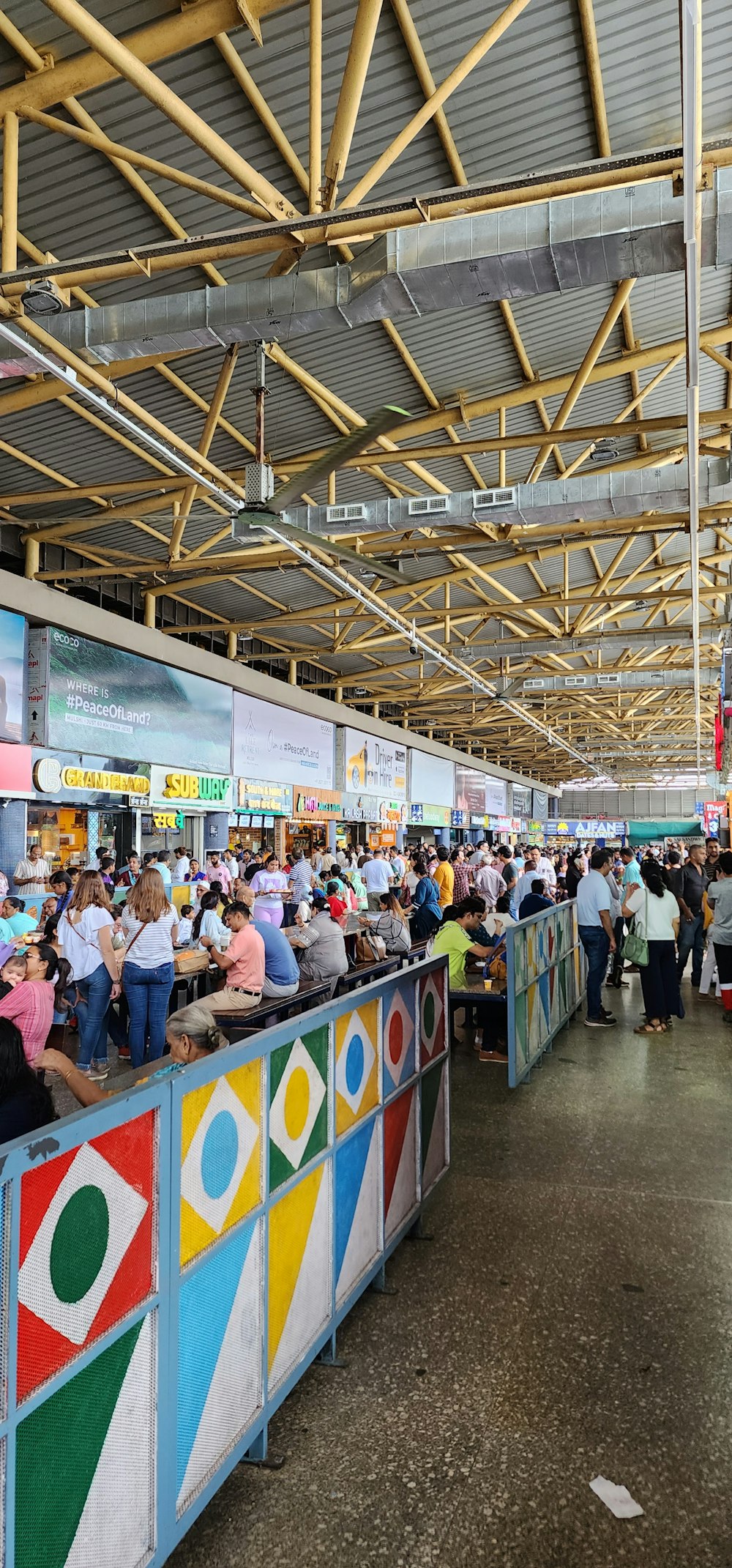 a large group of people standing around a food court