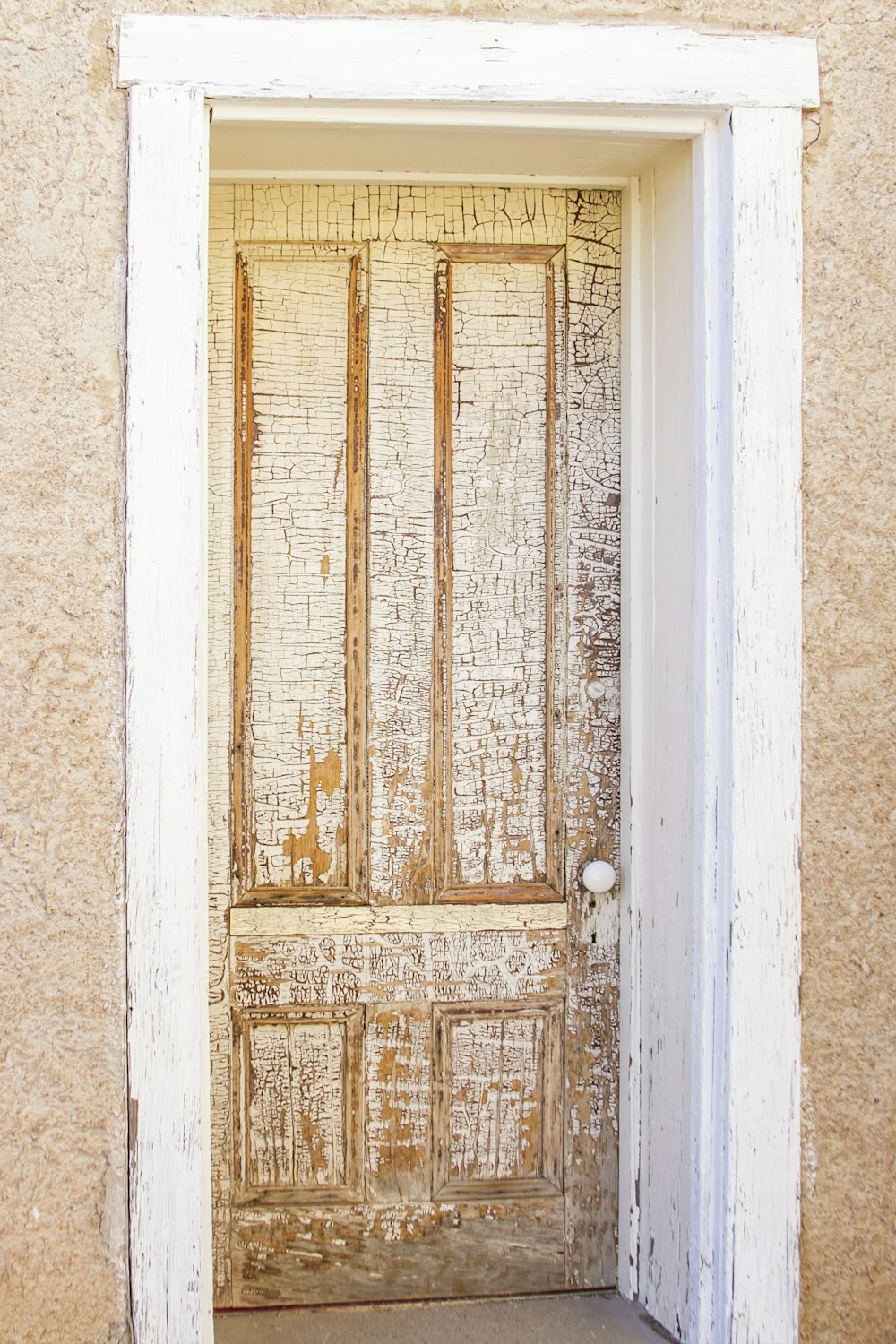 a wooden door with a white frame on a tan wall