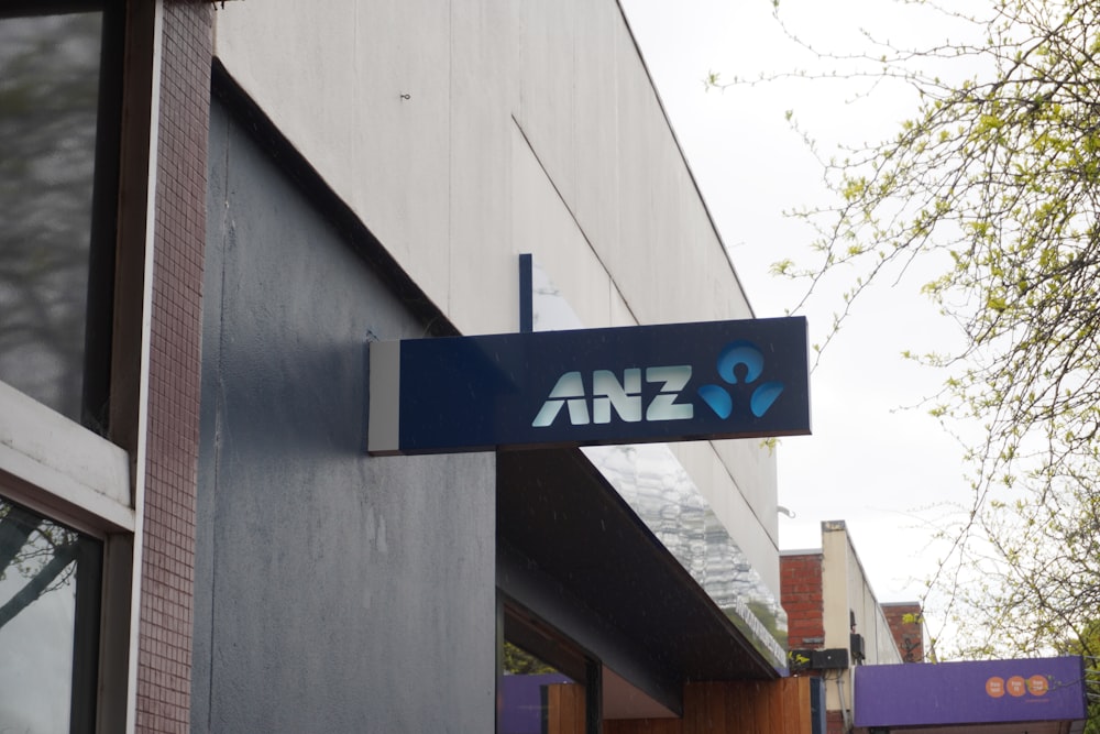a blue and white sign hanging from the side of a building