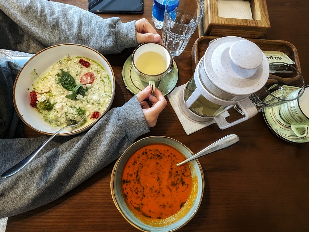 a person sitting at a table with a bowl of soup and a bowl of soup