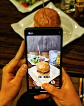 a person taking a picture of a hamburger