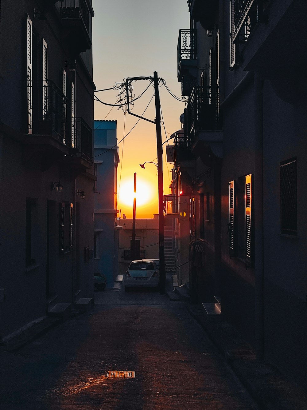 the sun is setting in the distance between two buildings