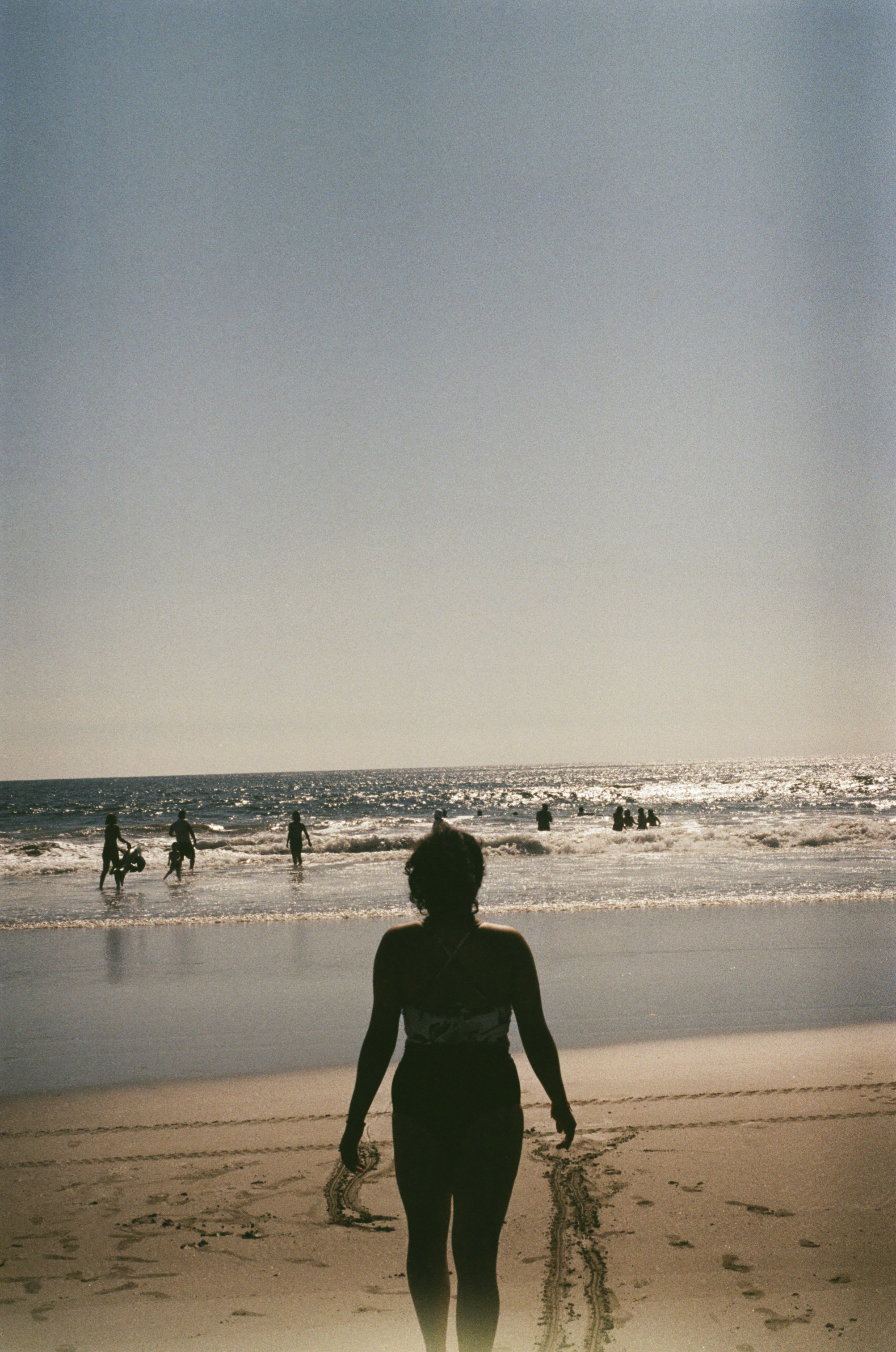 Una mujer en traje de baño caminando por la playa