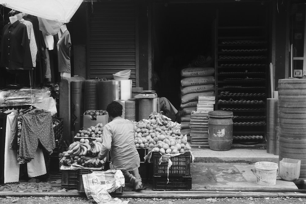 a black and white photo of a man selling produce