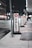Several valet signs are lined up along a city street at night. The signs are marked with a large red V and the word 'VALET' in bold black letters on a white background. The street is dimly lit, with buildings and streetlights visible in the background.