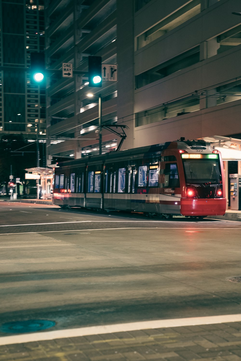 a red train traveling down a street next to a tall building