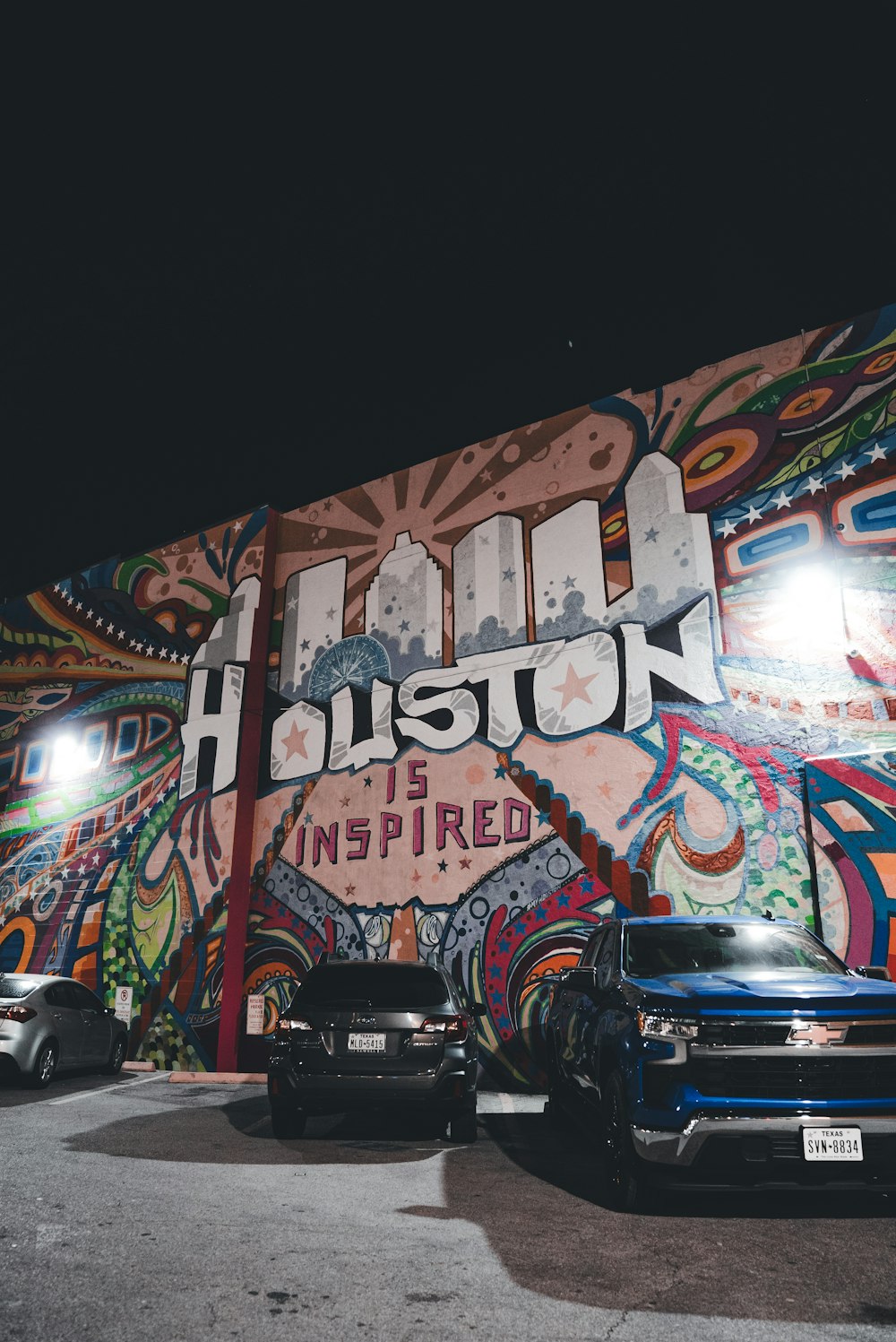 two cars parked in front of a building with a mural on it