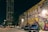 A vibrant street mural reads 'Houston is Inspired' with colorful patterns and shapes surrounding the text. Parked cars, including a blue Chevrolet, are visible in front of the mural. A tall building and street lamps illuminate the scene, creating a lively urban atmosphere at night.