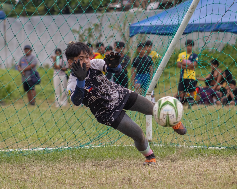 a young boy kicking a soccer ball on top of a field