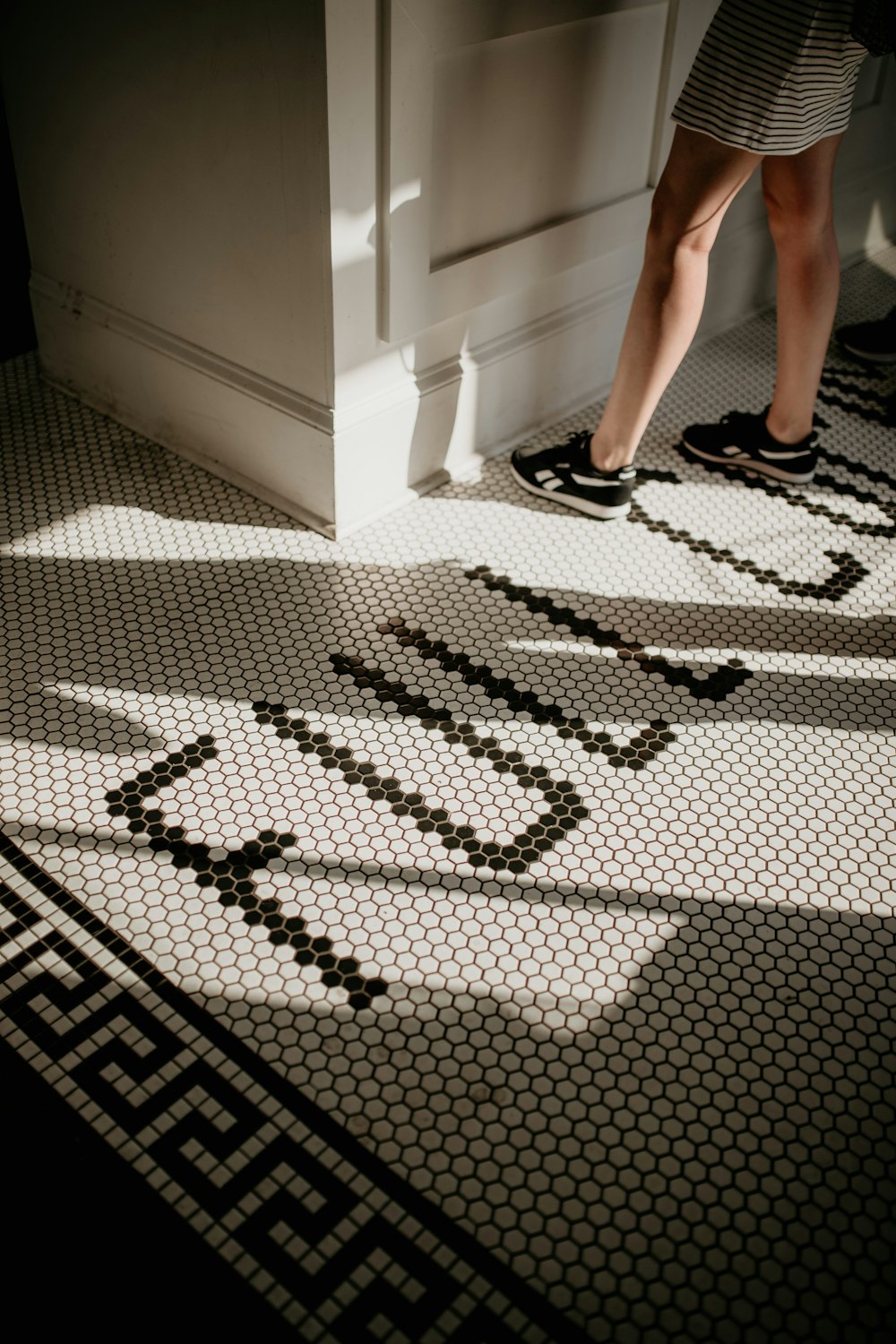 a woman standing on a tiled floor next to a doorway