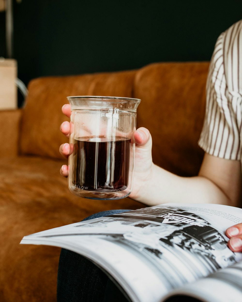 a person holding a book and a glass of liquid