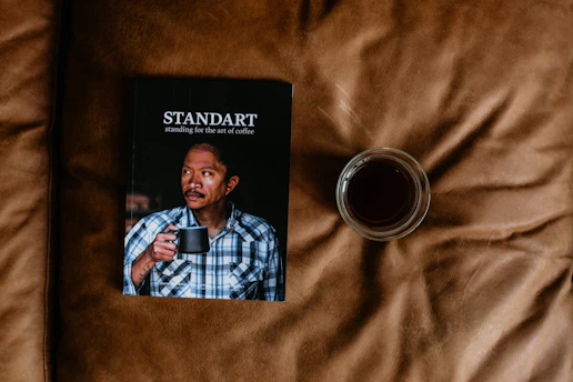 A close-up of the latest issue of plano 449 magazine resting on a wooden desk with a cup of coffee nearby.