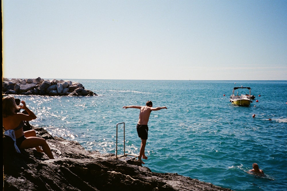 a man standing on top of a cliff next to the ocean