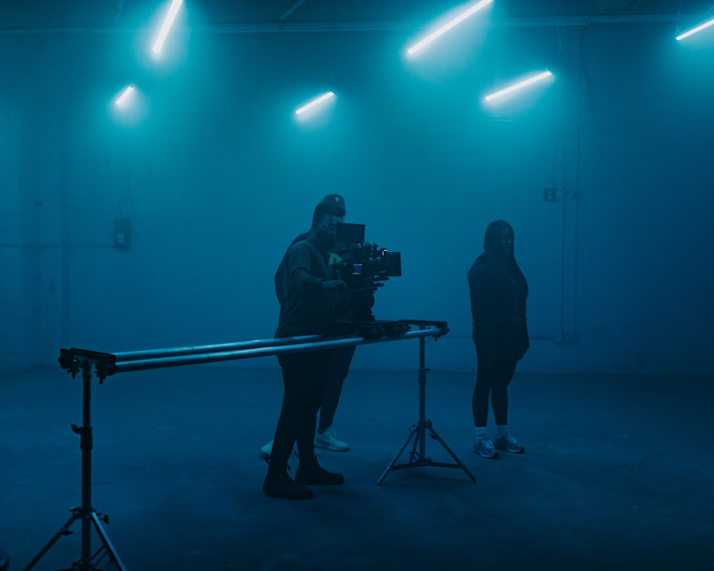 Un hombre parado frente a una cámara en una habitación oscura