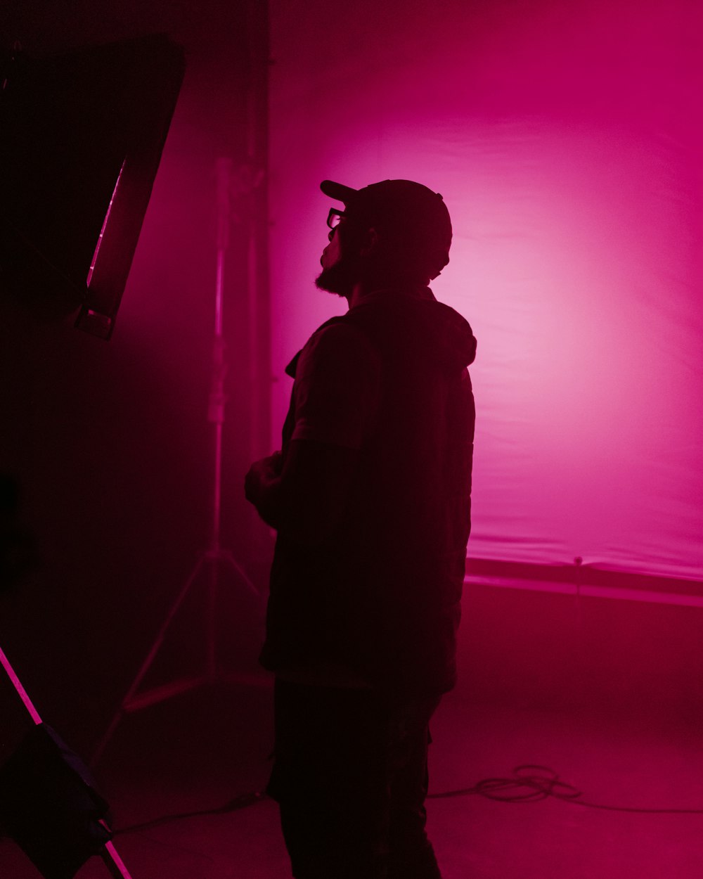Un hombre parado frente a una luz rosa