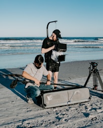 a man is filming another man on the beach