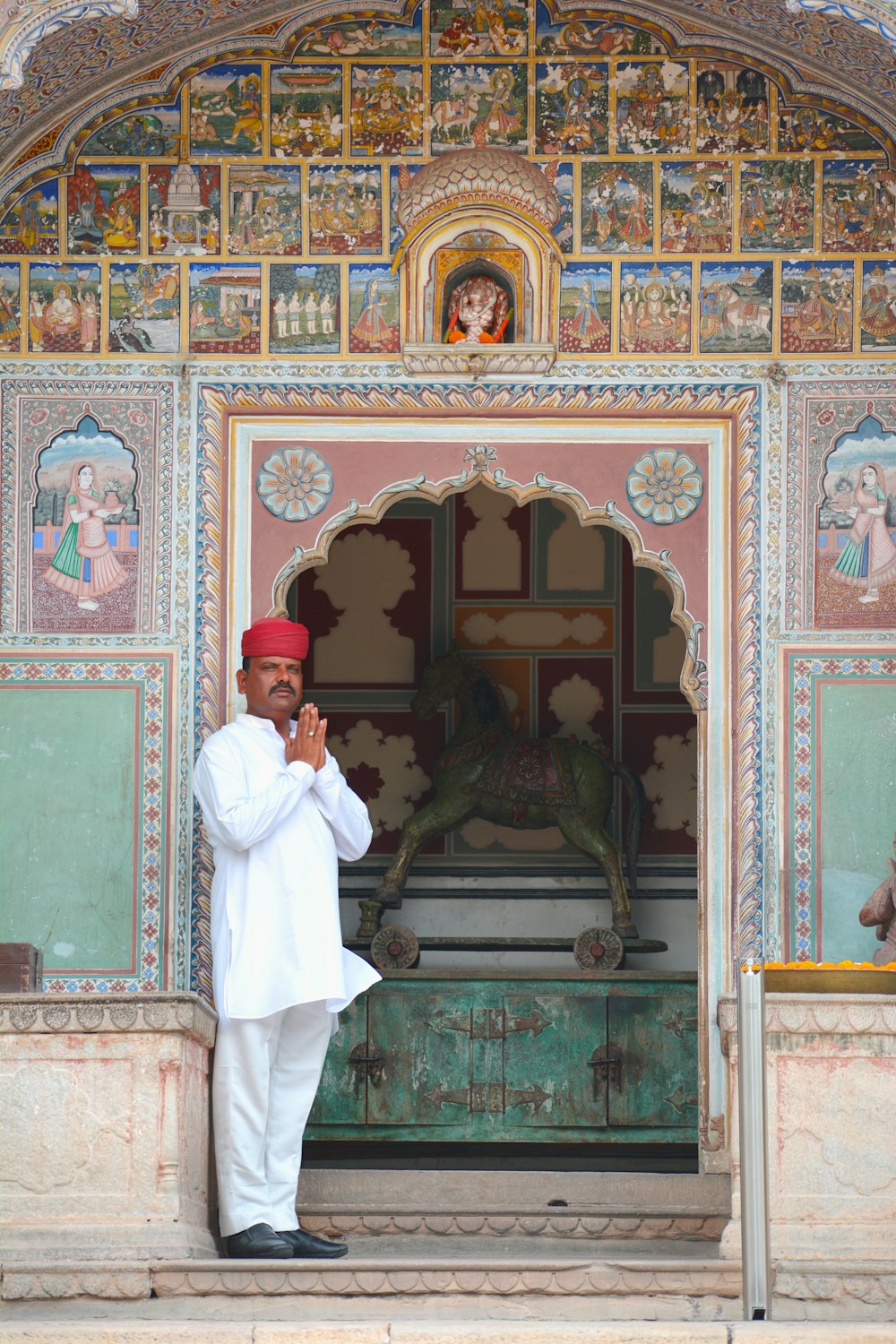 a man in a white outfit standing in front of a building