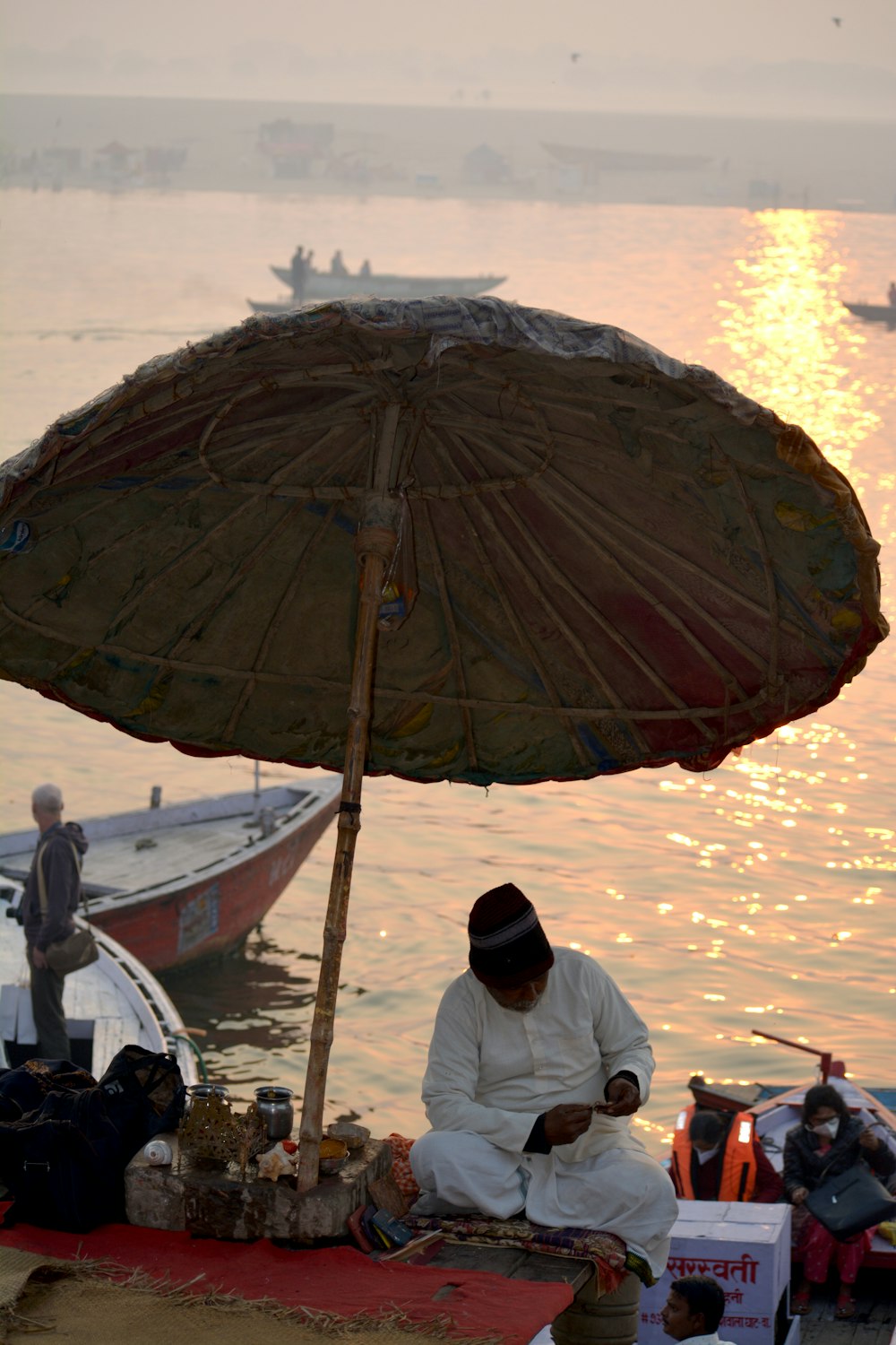 a man sitting under an umbrella next to a body of water