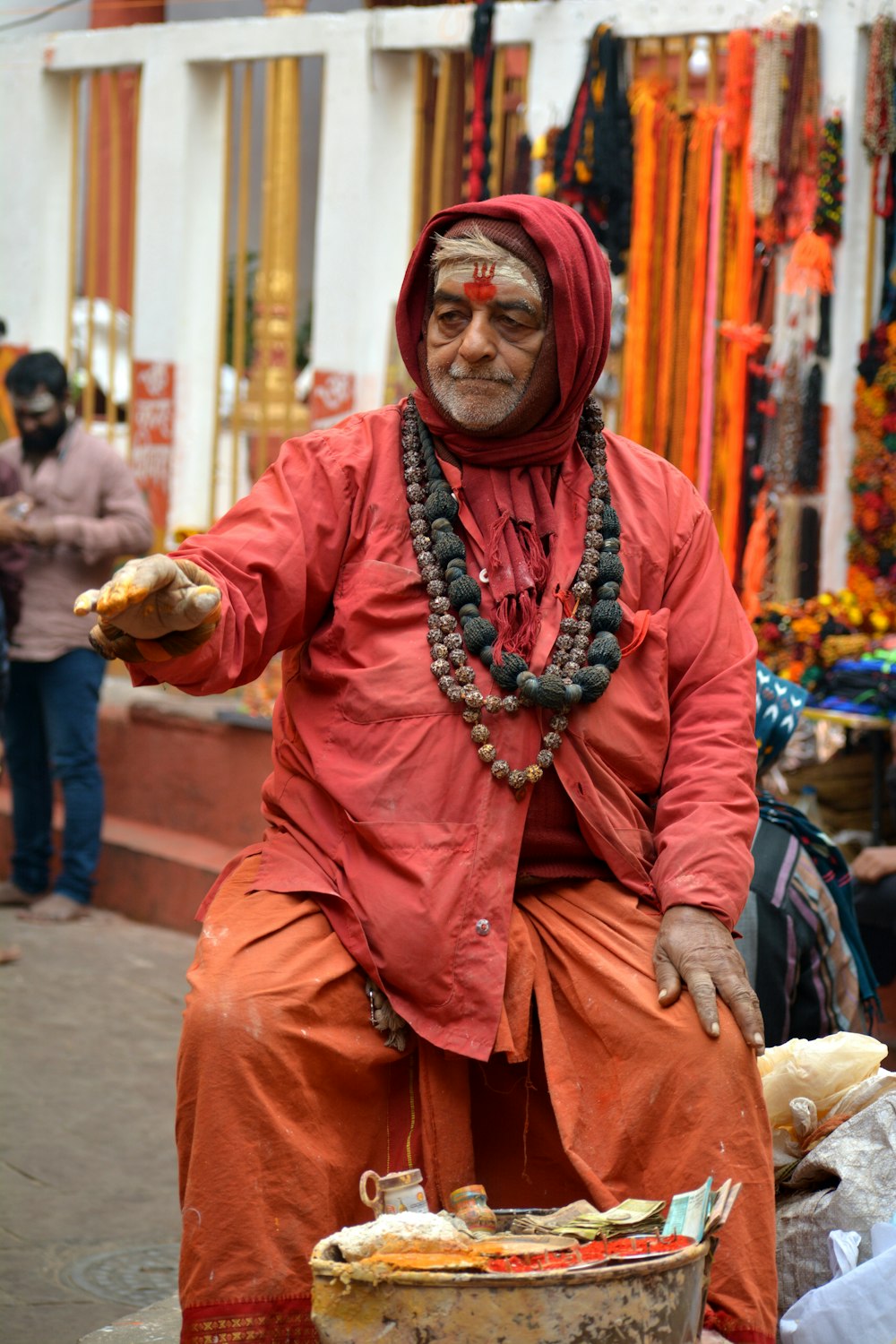 a man in a red outfit sitting on a bucket