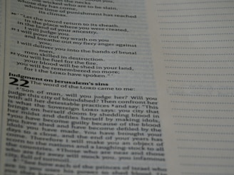 A close-up view of an open page from a book, likely a Bible, featuring printed text with headings and numbered verses. The right-hand side shows a blank lined section.
