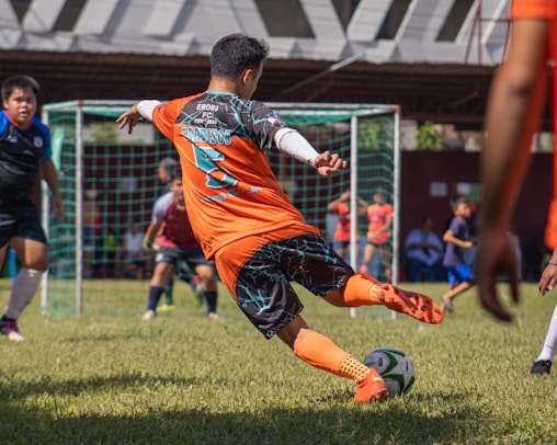 a young man kicking a soccer ball on a field