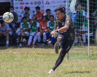a man kicking a soccer ball on top of a field