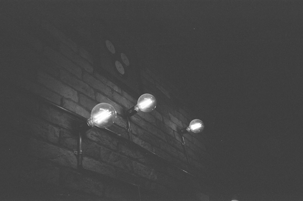 a black and white photo of street lights on a brick wall