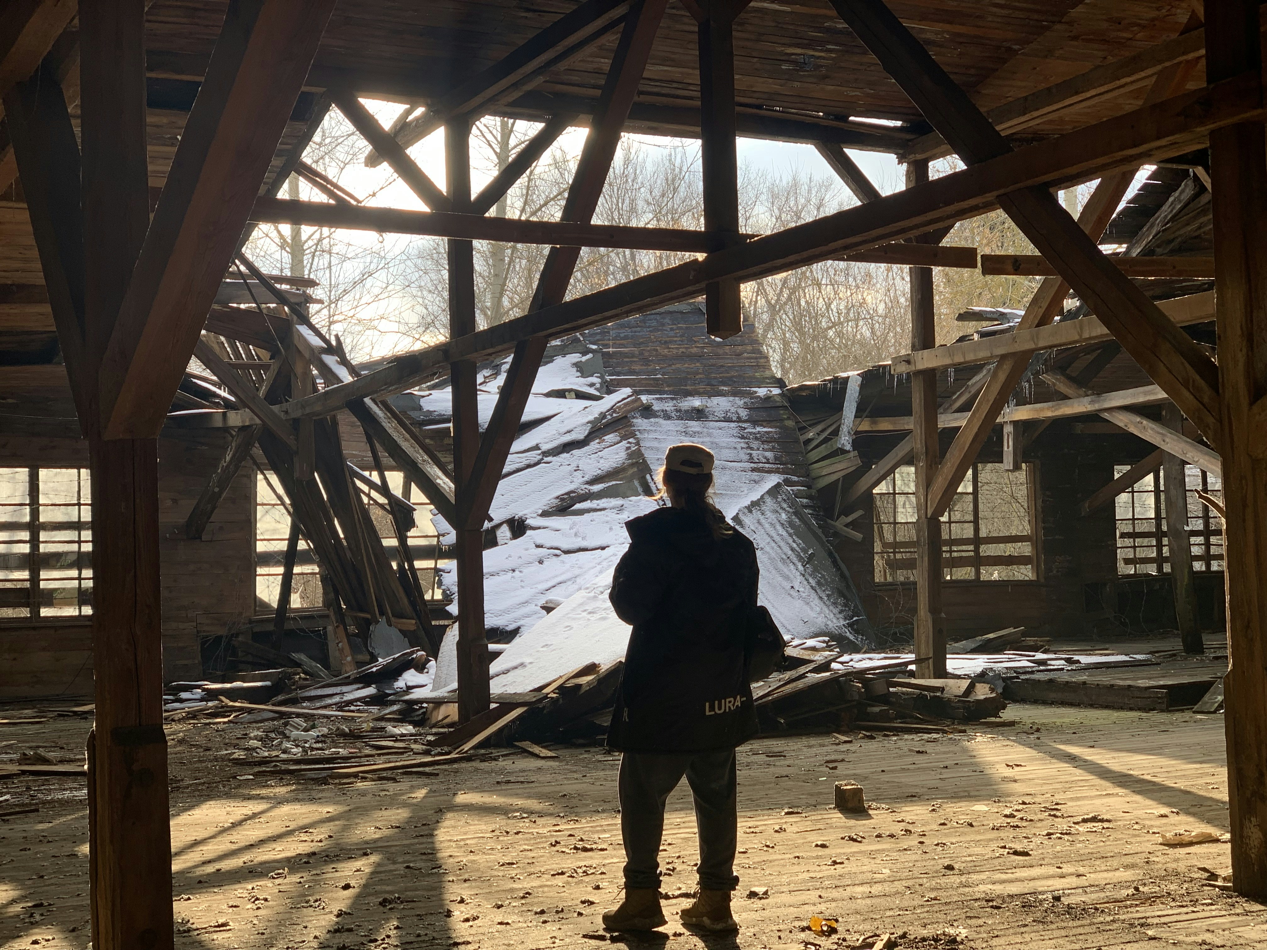 a person standing under a wooden structure in the snow