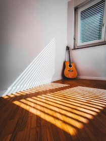 A warm, sunlit workspace with a guitar leaning against a desk, yellow accents glowing softly.